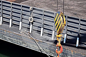 Loading coal from cargo barges onto a bulk carrier using ship cranes and grabs at the port of Muara Pantai, Indonesia. Close-up vi