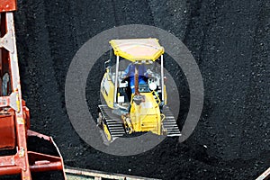 Loading coal from cargo barges onto a bulk carrier using ship cranes and grabs at the port of Muara Pantai, Indonesia. Close-up vi