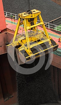 Loading coal from cargo barges onto a bulk vessel using ship cranes.