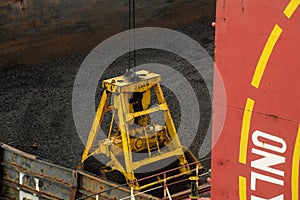 Loading coal from cargo barges onto a bulk vessel using ship cranes.