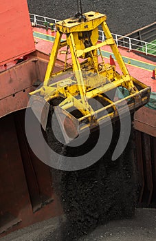 Loading coal from cargo barges onto a bulk vessel using ship cranes  in offshore coal cargo terminal.