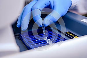 Loading a DNA tube into a PCR polymerase chain reaction thermocycler machine in a bioscience laboratory. Concept of science,