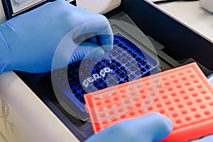 Loading a DNA tube into a PCR polymerase chain reaction thermocycler machine in a bioscience laboratory. Concept of science,