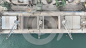 Loading dry cargo ship of sunflowers by cranes in port. Aerial view loading into holds of sea cargo vessel