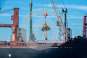 Loading dry cargo ship of wheat by cranes in port. Loading into holds of sea cargo vessel