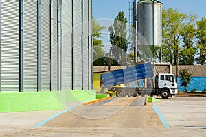 Loading grain by trucks onto the elevator into metal containers