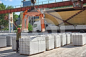 Loading pallets with white brick on a truck with a long body.