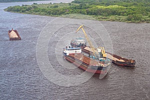 Loading sand into a barge on the river, transporting cargo by water