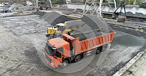 Loading a truck in the port, the excavator loads into the material in the truck