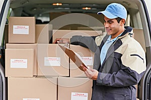 Loading the van for his day of deliveries. a delivery man standing next to a van full of boxes.