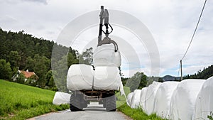 loading white grass rolls on country road in norway