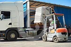 Loading works. Forklift with load and lorry truck