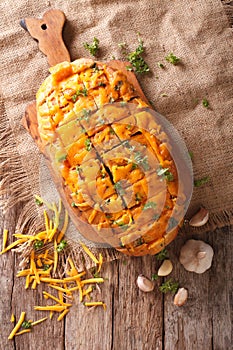 loaf of bread baked with cheddar cheese, garlic and herbs closeup. Vertical top view