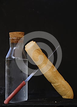 Una barra de pan de pan un cuchillo transición eso próximo sobre el una botella 