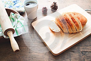Loaf of bread on wood background with cup of coffee and bakery tools