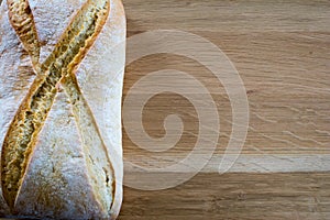 Loaf of bread on wooden oak table top.