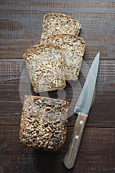 Loaf of fitness rye bread with ears of wheat on wooden board. View from above