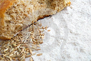 Loaf of fresh baked wheat and rye bread with grains and white flour on wooden table background photo