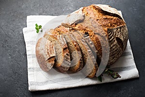 A loaf of fresh dark round buckwheat bread from a private bakery on a dark background on a vintage wooden cutting board