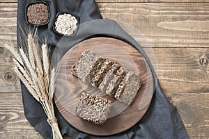 A loaf of fresh rustic whole rye bread on wooden table. Healphy food background. Top view. Copy space. Fitness photo