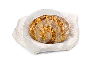 Loaf of freshly baked wheat bread on napkin on white background