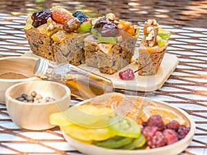 A loaf of fruit cake in wooden plate with defocused of dried fruit, spices and honey