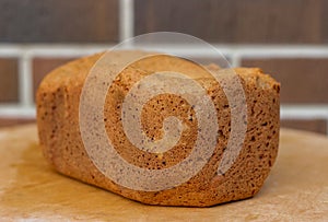 Loaf of homemade freshly baked bread on brown brick wall background