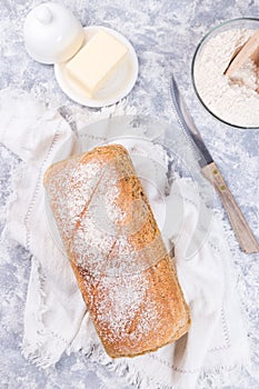 Loaf of homemade no knead sandwich bread with knife and butter, vertical, top view