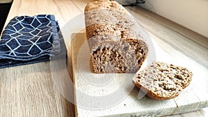 A loaf of homemade wholegrain bread on a wooden cutting board