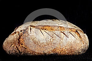 Loaf or miche of French sourdough, called as well as Pain de campagne, on display on a black background.