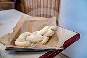 Loaf of raw uncooked swiss zopf dough braided and sitting on a stainless steel tray