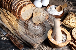 loaf of rye bread, ears of wheat, eggs and a bowl of flour. Close-up