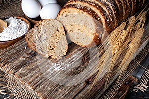 loaf of rye bread, ears of wheat, eggs and a bowl of flour. Close-up