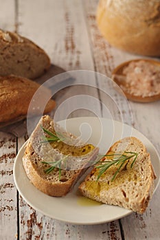 A loaf of rye bread with oil and rosemary in rustic style