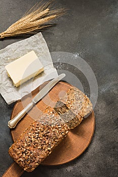 Loaf of rye bread with wheat and butter, sliced on cutting board. Close up. Copy space.