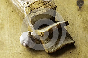 A loaf of sliced bread and a head of garlic lie on the cutting board