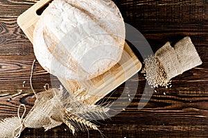 Loaf of white bread with ears wheat and corn lies