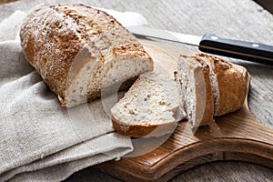 Loaf of whole wheat bread with slices on wooden board