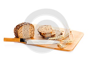 Loaf of wholemeal bread cutting into slices on wood board isolated