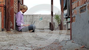 Loafing man sits on a construction site and works at his laptop