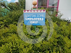 Loafing zone employees only sign and green plants