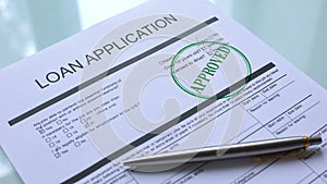 Loan application document approved, hand stamping seal on official paper closeup