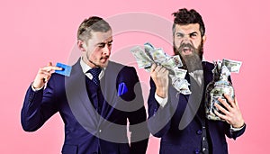 Loan and banking concept. Men in suit, businessmen with jar full of cash and credit card, pink background. Mature man on