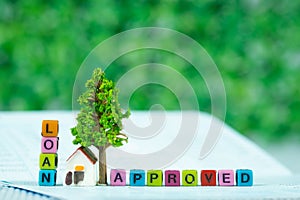 LOAN text and small model house and little tree with notebook, s