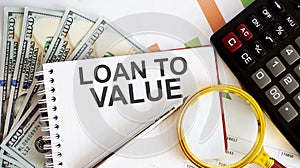 LOAN TO VALUE is written on notebook on a chart background with dollars and calculator