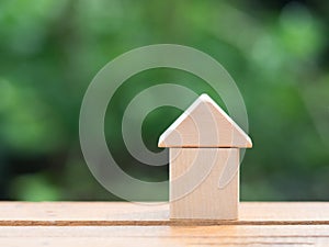 Loans real estate home concept. Wooden house miniature on wooden floor with blur green background.