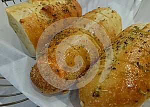 Loaves of garlic bread in a wire basket with wax