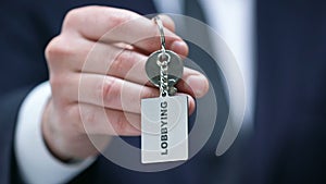 Lobbying word on keychain in male politician hand, governmental influence