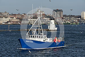 Lobster boat Direction passing lighthouse in New Bedford harbor