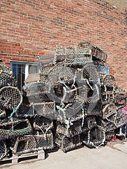 Lobster pots used in fishing for crustaceans stacked against a building in scarborough harbour